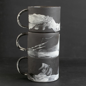 Three stacked black and white mugs