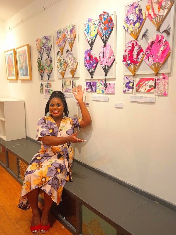 Victoria sitting under her wall fan display.