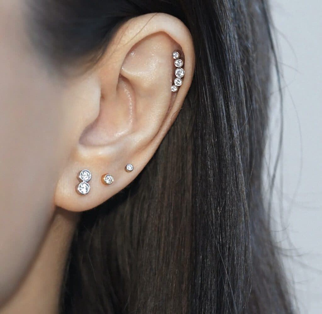 Curated ear styling with diamond studs and climbing helix earring in 18K white gold. Lena Cohen Jewellery London fine piercing jewellery, handcrafted minimalist design.