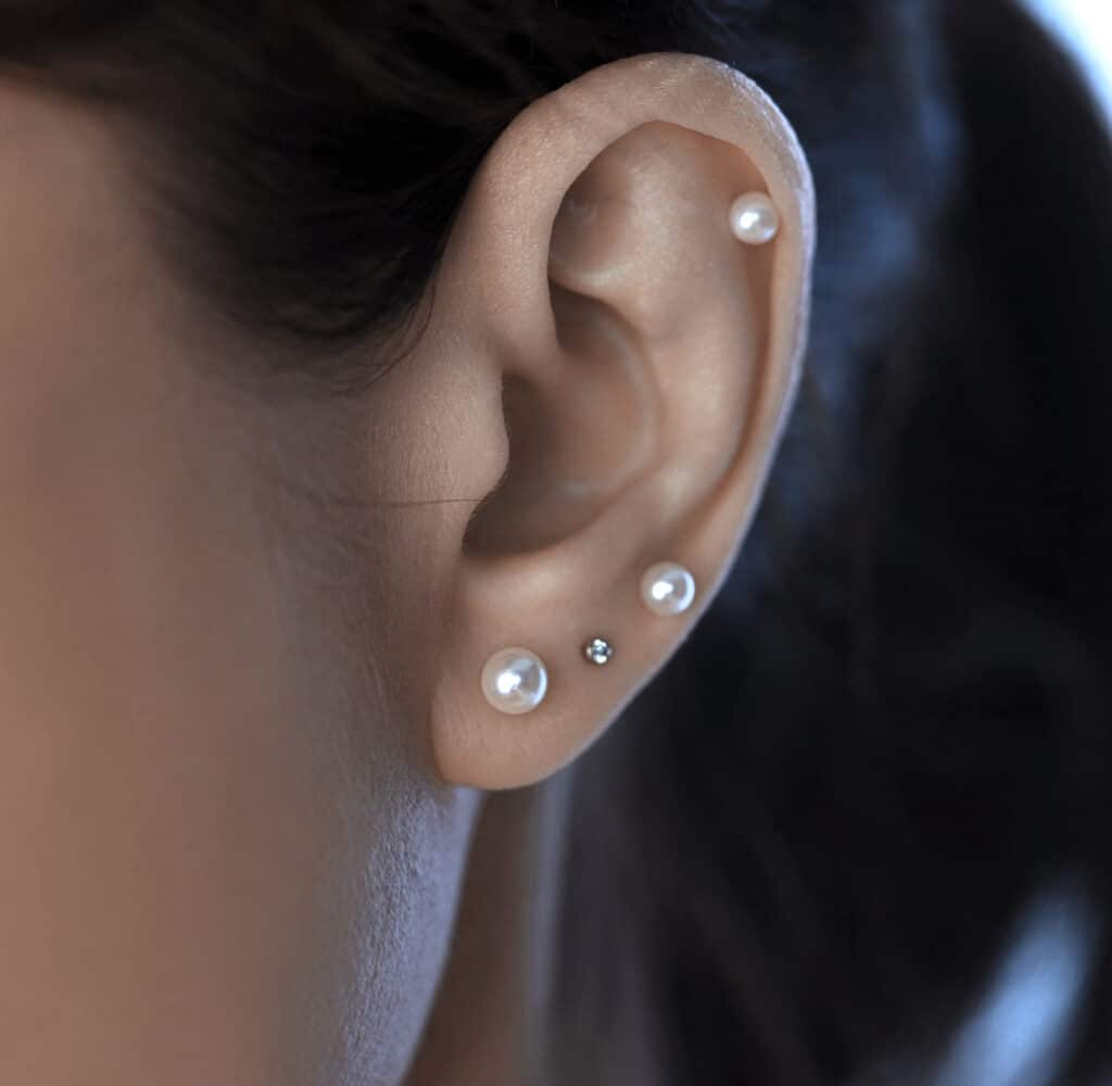 Curated ear with pearl flat-back studs in 18K solid gold. Lena Cohen Jewellery London fine piercing jewellery, minimalist quiet luxury design.