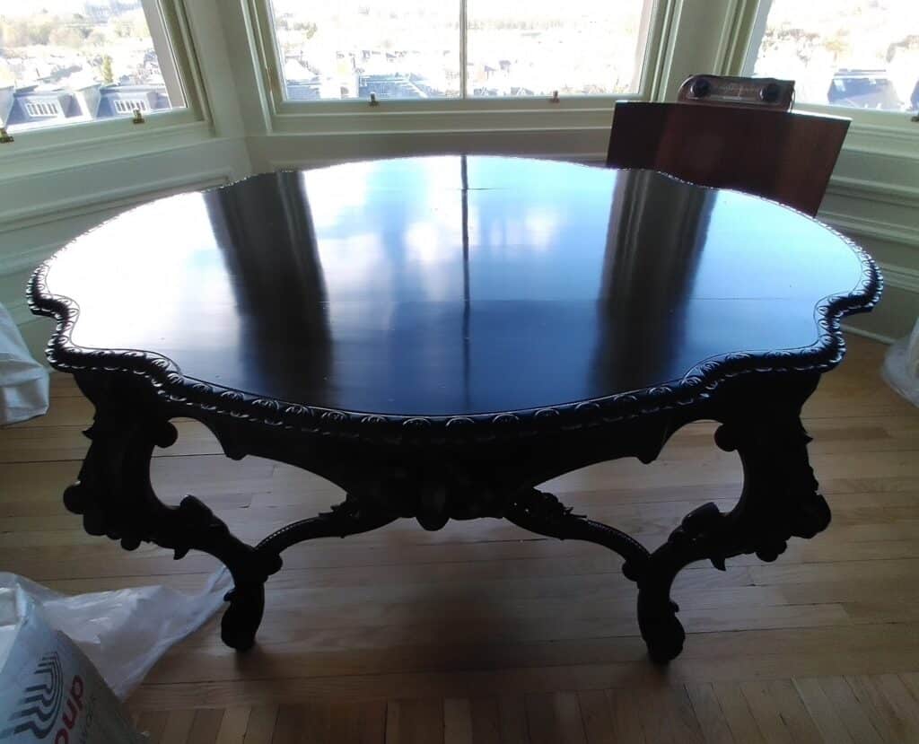 An antique table which we made new carved sections for the missing pieces around the edge. We then cleaned the whole piece, touched up the legs and apron and then French polished the top.